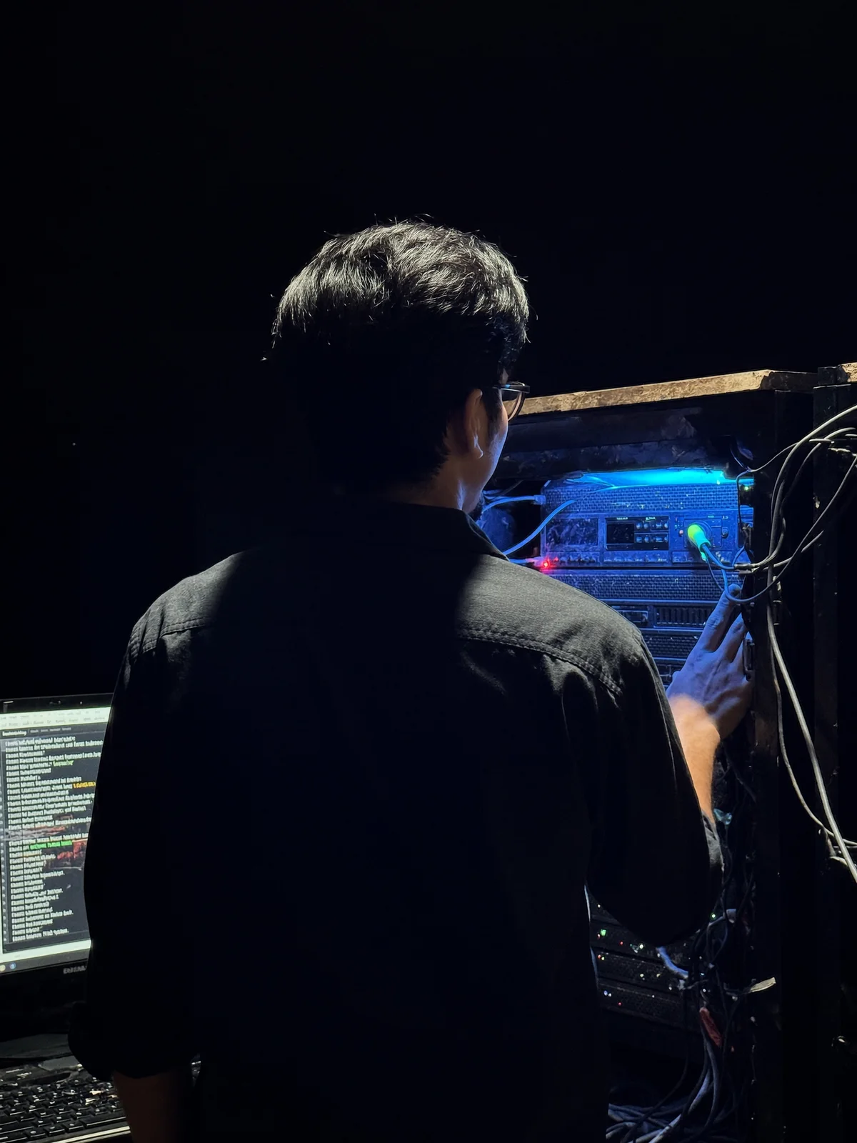 Seen from behind, working on a server rack lit in blue in a home lab